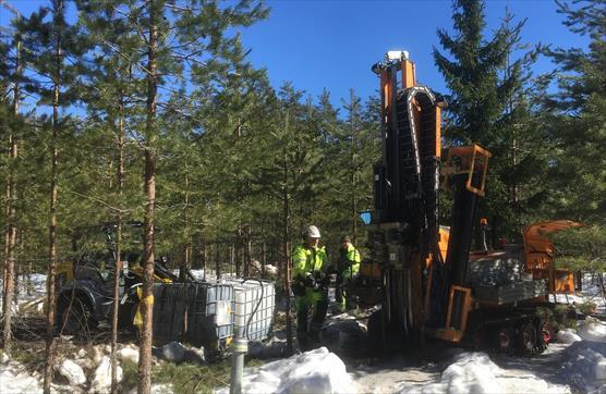 Talvinen metsä, jossa kairavaunu ja säiliöitä.