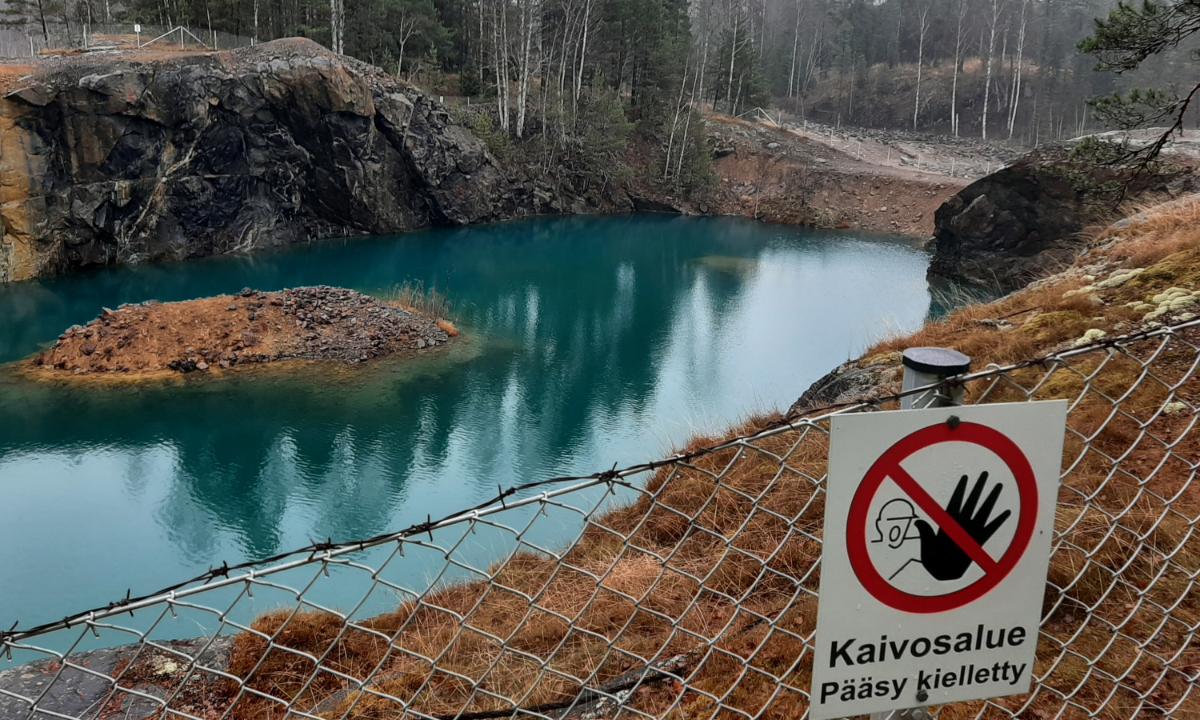 Kuvassa on kaivosalue ja vettä. Etualalla on kyltti, jossa lukee Kaivosalue, pääsy kielletty.