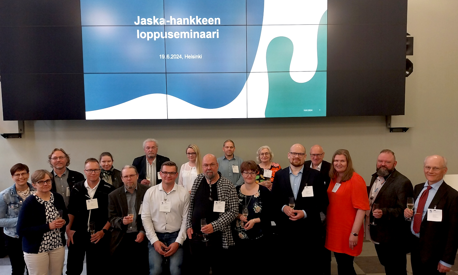 Kuvassa on joukko ihmisiä suuressa salissa ja taustalla näkyy valokangas, jossa lukee Jaska-hankkeen loppuseminaari.