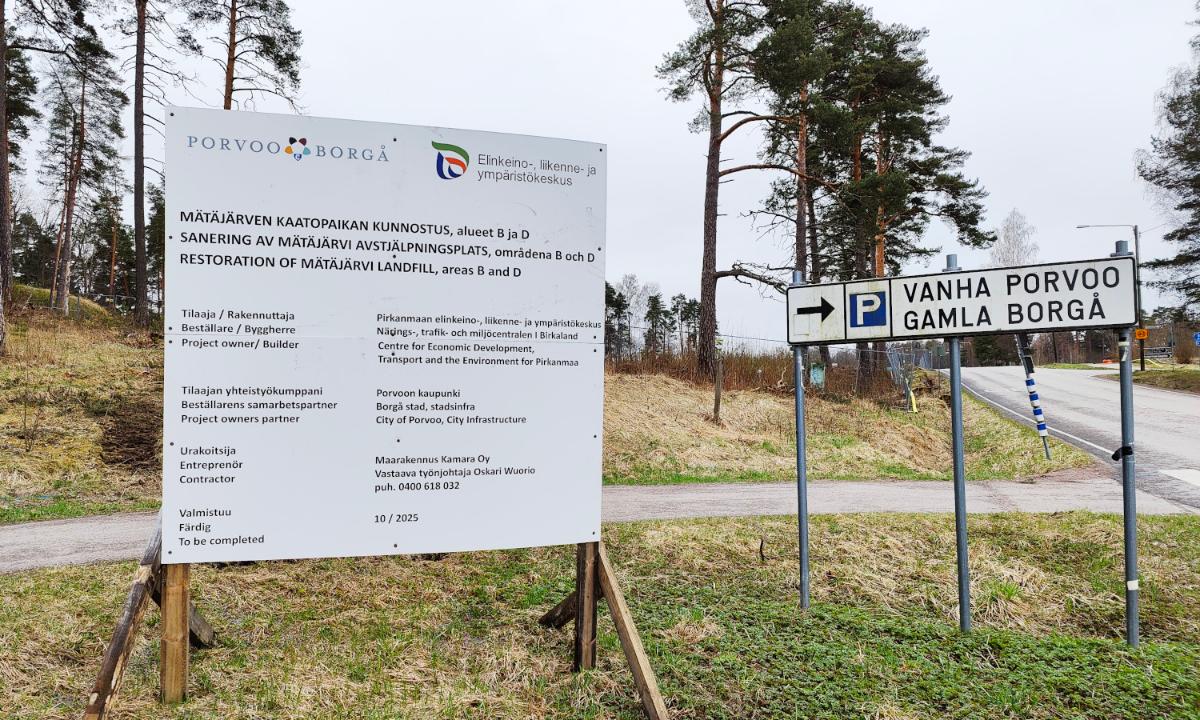 Kuvassa on työmaakyltti ja peltomaisemaa.