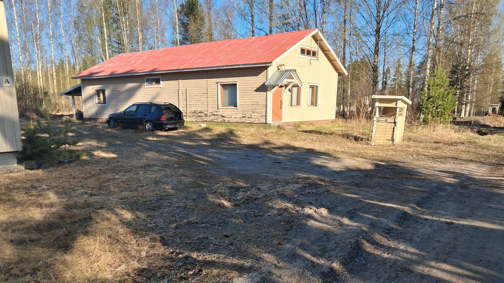 Kuvassa näkyy kaksi puista rakennusta ja pihaa.